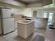 Bright eat-in kitchen featuring island with cooktop, white appliances, tile floors, and plenty of cabinet space at 9685 Southern Belle Dr, Weeki Wachee, FL 34613