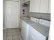 Bright laundry room with a washer, dryer, sink, white cabinets, and tile floors at 9685 Southern Belle Dr, Weeki Wachee, FL 34613