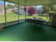 View of the screened lanai with table, chairs, and manicured lawn with mature landscaping in the background at 9685 Southern Belle Dr, Weeki Wachee, FL 34613