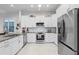 Well-lit kitchen showcasing white cabinets, granite countertops, and stainless steel refrigerator and oven at 10391 Coquina Ct, Placida, FL 33946