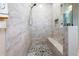 Luxurious shower with floor-to-ceiling marble tiles, a built-in bench, and mosaic tile flooring at 10391 Coquina Ct, Placida, FL 33946