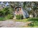 Charming A-frame home with a metal roof, nestled among mature trees and landscaping at 8309 Oakgren Rd, Brooksville, FL 34601
