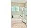 Bathroom featuring a large soaking tub, glass-enclosed shower, and plantation shutters at 1138 Lumsden Trace Cir, Valrico, FL 33594