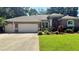 Charming single-story home featuring a well-manicured lawn, three-car garage, and mature landscaping at 1138 Lumsden Trace Cir, Valrico, FL 33594