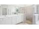 Bathroom featuring double sinks, white cabinetry, large mirror and glass shower at 11296 Curio Dr, Brooksville, FL 34613