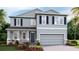 Two-story home featuring stone accents, gray siding, dark shutters, and a two-car garage at 11352 Curio Dr, Brooksville, FL 34613