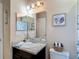 Bathroom with vanity sink, modern lighting, mirror, toilet, decor, plus a shower-tub combo (partially visible in mirror) at 6812 Gideon Cir, Zephyrhills, FL 33541