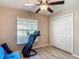 Bedroom featuring a window, ceiling fan, closet and light wood flooring with a blue futon and exercise equipment at 6812 Gideon Cir, Zephyrhills, FL 33541