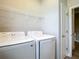 Laundry room features a new white washer and dryer with overhead shelving for convenient storage at 3018 Oceanside St, North Port, FL 34286