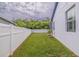Green backyard with a white fence, lawn and a mature shade tree with a home in the background at 205 Bengal Cir, Oldsmar, FL 34677
