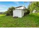 View of backyard, featuring a storage shed with wooden access steps, surrounded by lush green grass and shrubbery at 5728 Colonial Dr, New Port Richey, FL 34653