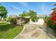 Charming single-story home featuring a covered carport, lush landscaping, and a flagpole with the American flag at 5728 Colonial Dr, New Port Richey, FL 34653