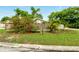 Street-view of a fenced front yard adorned with colorful flowering bushes and mature palm trees at 5728 Colonial Dr, New Port Richey, FL 34653