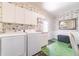 Bright laundry room with side by side washer and dryer, green tile floor, and overhead cabinets at 15200 Rawls Rd, Sarasota, FL 34240