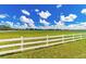 Scenic view of the property with bright green grass and white fencing under a blue sky at 15200 Rawls Rd, Sarasota, FL 34240