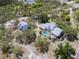 Aerial view showcasing the home with a screened-in pool and detached garage on a wooded lot at 10230 289Th E St, Myakka City, FL 34251
