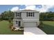 Two-story home featuring stone accents, gray siding, shutters, landscaped yard, and a two-car garage at 10484 Tucker Rd, Weeki Wachee, FL 34613