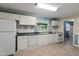 Classic kitchen featuring standard white appliances, bright natural light, and a view into the bathroom at 304 Highland St, Brooksville, FL 34601
