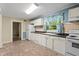 The kitchen has white appliances, ample cabinet space, and a bright window with floral curtains at 304 Highland St, Brooksville, FL 34601