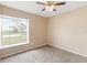 Sunny room features a large window and neutral paint, with carpet flooring and ceiling fan at 14150 Prospect St, Spring Hill, FL 34609