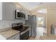 Galley kitchen boasts stainless appliances, granite countertops, and a tiled backsplash at 14150 Prospect St, Spring Hill, FL 34609
