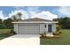 Charming single-story home with a gray exterior, two-car garage, and tropical landscaping for curb appeal at 30846 Wild Juniper Ct, Brooksville, FL 34602