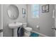 Stylish half-bath featuring a pedestal sink, toilet, and decorative nautical-themed art at 14347 Easy Goer St, Ruskin, FL 33573