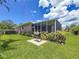 The backyard features a lush lawn, mature landscaping, a grill, and a screened-in porch at 1137 Indian Rocks S Rd, Largo, FL 33770