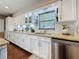 Well-lit kitchen featuring white cabinets, granite countertops, stainless steel dishwasher, and tiled backsplash at 1137 Indian Rocks S Rd, Largo, FL 33770