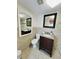 Well-lit bathroom with tile floors, granite countertop vanity, toilet, and decorative mirrors at 6806 Monique Ave, Tampa, FL 33625