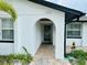 Close-up of the arched entryway showcasing brick flooring, white stucco exterior, and tropical landscaping at 6806 Monique Ave, Tampa, FL 33625