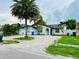 Inviting white home with an arched entryway, a brick driveway, mature trees and lush landscaping at 6806 Monique Ave, Tampa, FL 33625