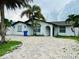 Charming home with brick driveway, white stucco exterior, and tropical landscaping creates curb appeal at 6806 Monique Ave, Tampa, FL 33625