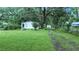 A quaint home surrounded by a lush lawn and trees, featuring a driveway leading to the backyard at 242 Zoller St, Brooksville, FL 34601