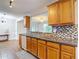 Traditional kitchen with wood cabinets, stainless sink, mosaic backsplash, and view into living room at 7318 Tranquil Dr, Spring Hill, FL 34606