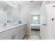 Bright bathroom featuring double sinks with white cabinets and an open doorway to the shower at 5528 Summer Sunset Dr, Apollo Beach, FL 33572