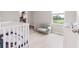 Cozy Bedroom with a white crib, soft chair, and bright window overlooking the yard at 5528 Summer Sunset Dr, Apollo Beach, FL 33572