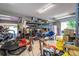 Garage with storage shelves, lawn equipment, refrigerator, and open garage door at 6628 1St N St, St Petersburg, FL 33702
