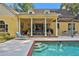 Inviting pool area with a spacious patio, covered pergola and a charming yellow house at 8608 Poinsettia Dr, Temple Terrace, FL 33637