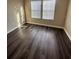 Neutral bedroom featuring dark wood-look floors, two windows, and white baseboards at 11928 Frost Aster Dr, Riverview, FL 33579