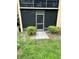Screened patio entrance with a paved walkway, framed by green bushes in a well-maintained outdoor setting at 24 Quails Run Blvd # 3, Englewood, FL 34223