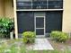 Back patio entrance enclosed with screens, set amidst green bushes and a peaceful outdoor landscape at 24 Quails Run Blvd # 3, Englewood, FL 34223