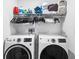Laundry room features two modern washing machines, overhead shelving, and organized laundry supplies at 5327 New Friendship Pl, Tampa, FL 33619