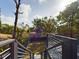 A view of a house backyard with a black fence and mature trees taken from the second-story deck and stairs at 1793 N Fort Harrison Ave, Clearwater, FL 33755