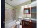 Modern bathroom featuring a bathtub with shower, toilet, and stylish sink with a red vanity at 1793 N Fort Harrison Ave, Clearwater, FL 33755