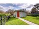 Detached garage with a gray exterior, red door, and manicured lawn at 5406 Fishhawk Ridge Dr, Lithia, FL 33547