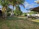 A large backyard with grass, trees, a lawn mower, and a covered patio on the side at 6006 12Th E St, Bradenton, FL 34203