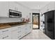 White kitchen with black appliances and granite countertops at 722 Pinellas Bayway S # 102, St Petersburg, FL 33715