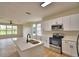 Modern kitchen with stainless steel appliances, white cabinets, and a kitchen island overlooking the living area at 11606 Tropical Isle Ln, Riverview, FL 33579