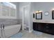 Spa-like bathroom featuring a soaking tub, large window, dual sink vanity, and blue accents at 764 S Mccall Rd, Englewood, FL 34223